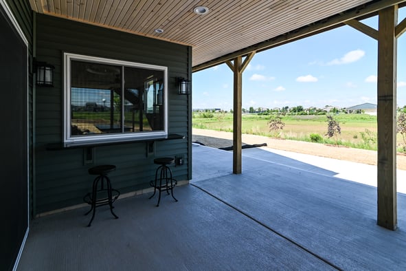 An exterior shot of a covered porch with a window and bar setup.