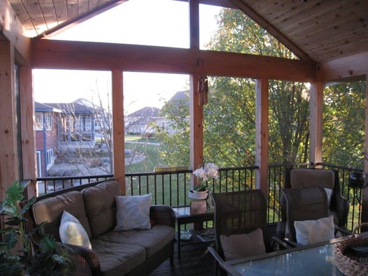 A fully furnished three season porch looking over the backyard.