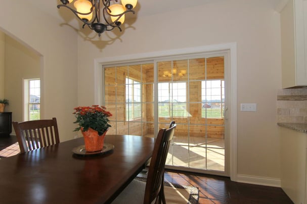 The view from the interior dining room looking into the three season porch with no furniture inside and wooden walls.