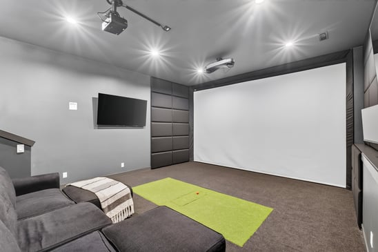 A completed basement entertainment area that works as an movie theatre with a large screen.